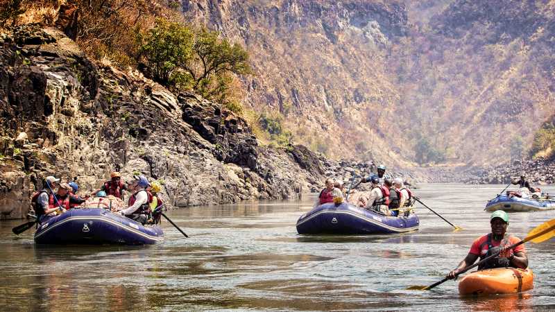 Paddling a calmer stretch of the Zambezi River while taking in the scale of Batoka Gorge - Zambezi River: Whitewater Rafting & Safari, Zambia