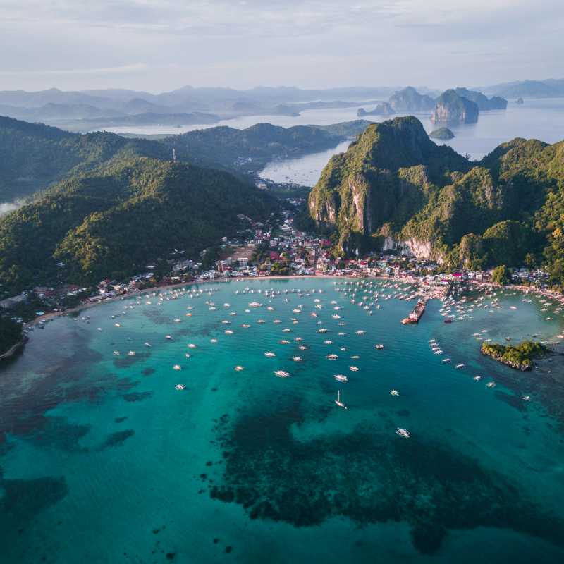A sweeping aerial perspective of El Nido reveals its sheltered bay, emerald waters and surrounding limestone peaks. | Eibner Saliba