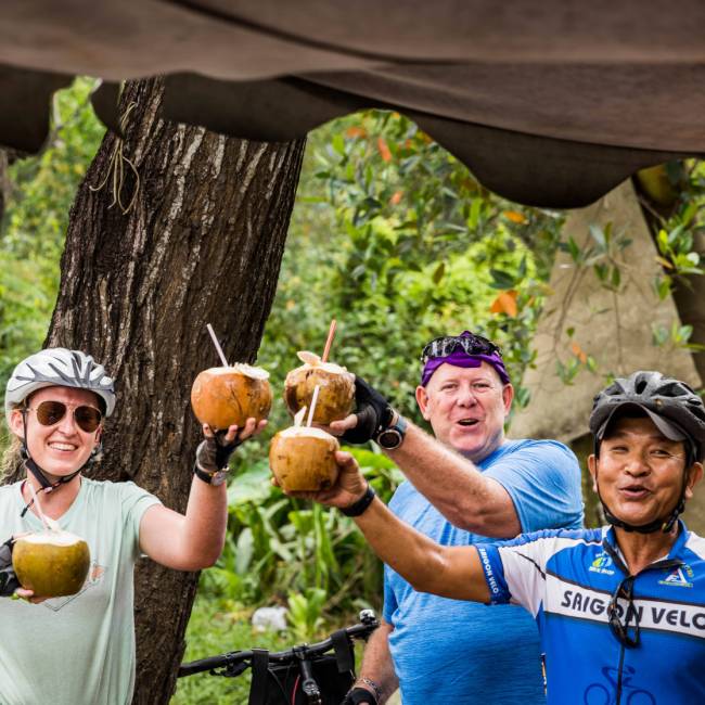 Cyclists enjoying a refreshing coconut roadside in Vietnam | Lachlan Gardiner