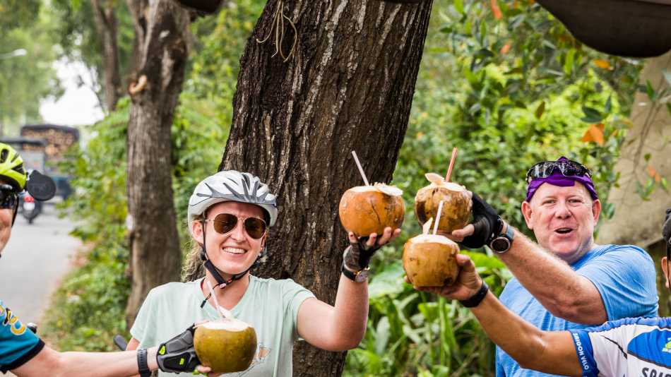 Cyclists enjoying a refreshing coconut roadside in Vietnam | Lachlan Gardiner