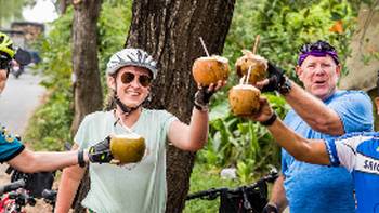 Cyclists enjoying a refreshing coconut roadside in Vietnam