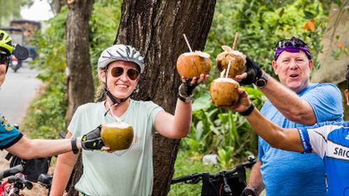 Cyclists enjoying a refreshing coconut roadside in Vietnam | Lachlan Gardiner