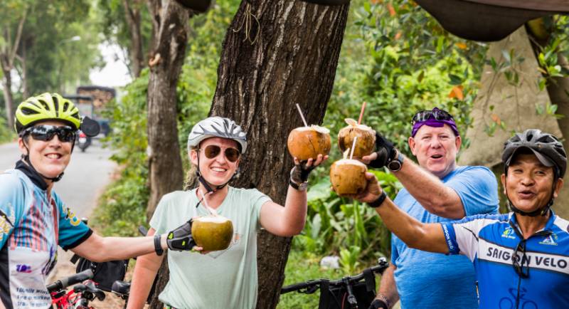 Cyclists enjoying a refreshing coconut roadside in Vietnam |  <i>Lachlan Gardiner</i>