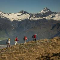 Trekkers on Buchanan peak with Mount Aspiring behind, walking above Matukituki valley, near Lake Wanaka | Colin Monteath