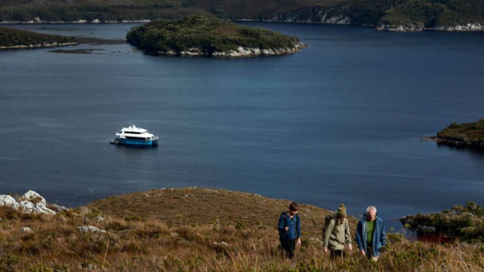 Guests on hike to Mt Stokes, Odalisque III in the entrance to Bathurst Channel | Tim Grey