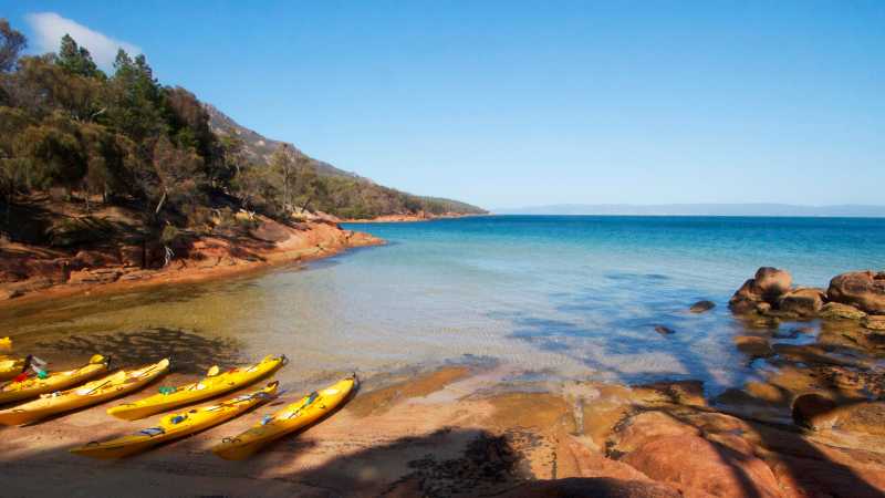 Kayaks resting on a remote Tasmanian beach | Amy Russell