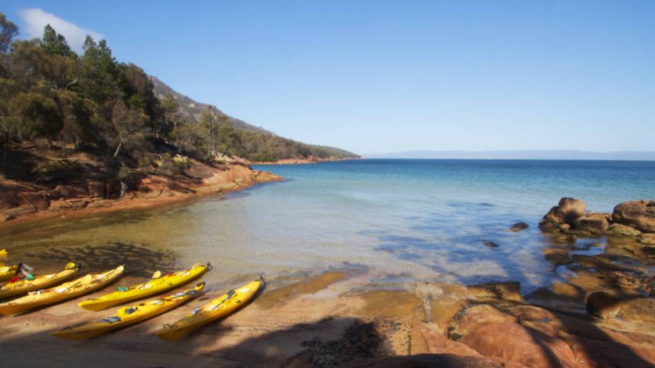 Kayaks resting on a remote Tasmanian beach | Amy Russell