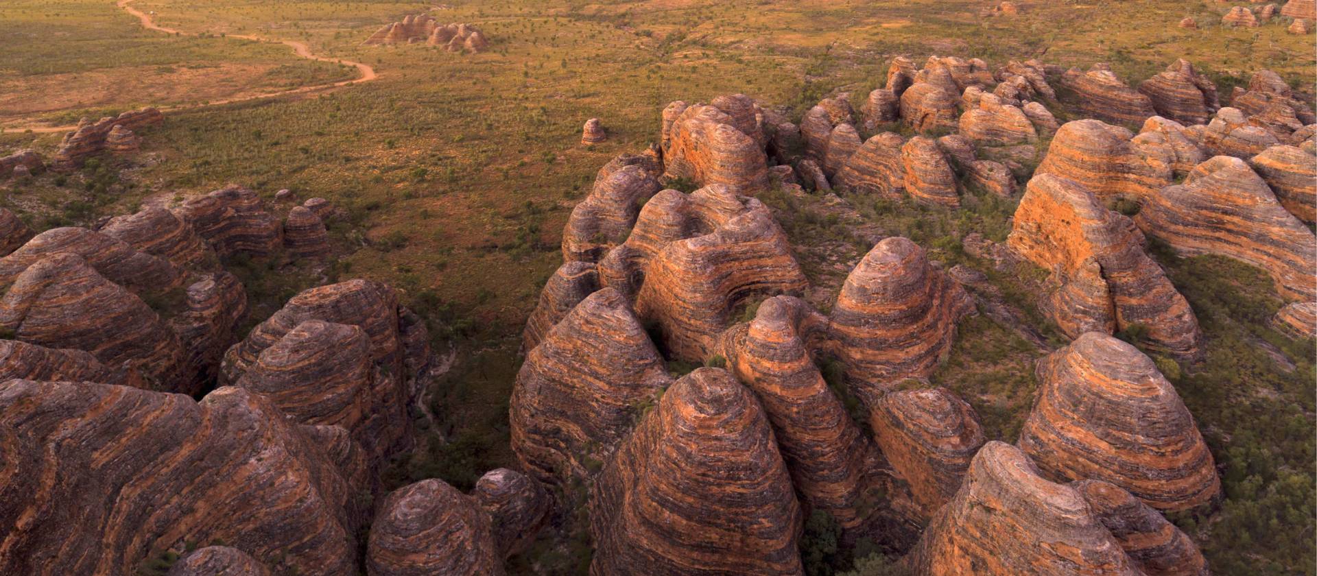 Indulge in the enchanting spectacle of a sunset casting its warm hues against the iconic Beehive Range in the Bungle Bungles | Tourism Western Australia