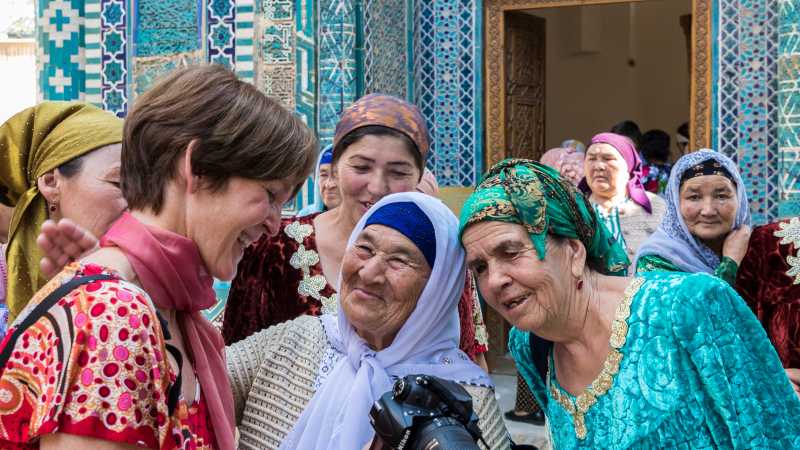 Pilgrims with traveller at Shah-i-Zinda, avenue of mausoleums, Samarkand | Richard I'Anson