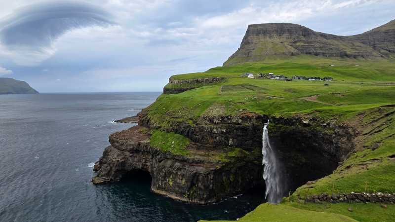 Waterfall plunging into the North Atlantic beneath a remote Faroese village - Faroe Islands: Kayaking the North Atlantic, Faroe Islands