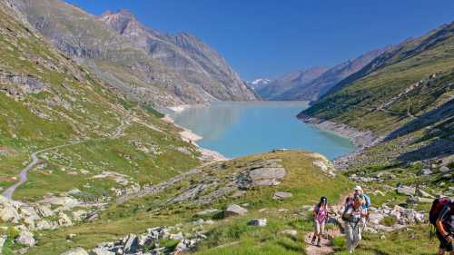 Group ascending a mountain on the Tour de Monte Rosa Walk above a stunning alpine lake | Andrew Bain