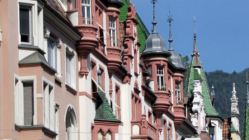 Bolzano townhouses with ornate turrets and green tiled roofs against a mountain backdrop - Alps to Aperitivo: Northern Italy with Ben Groundwater, Italy