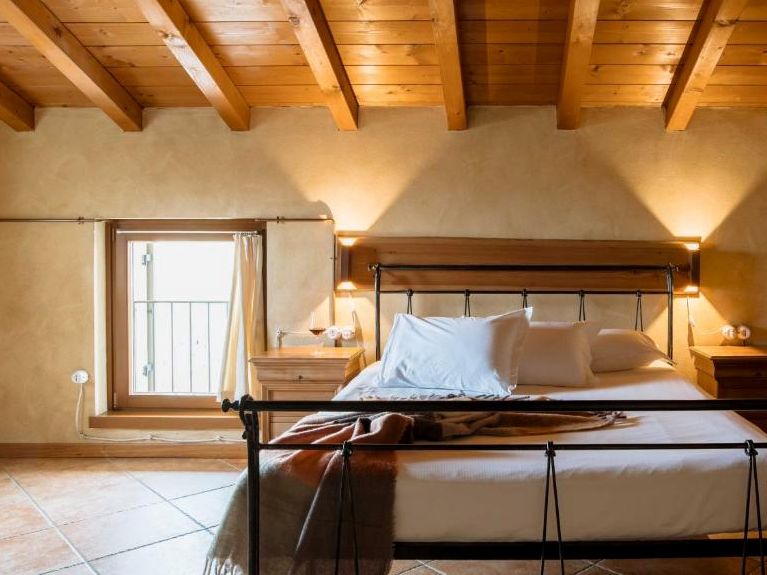 Valpolicella farmhouse bedroom with timber-beamed ceiling and antique iron bed
