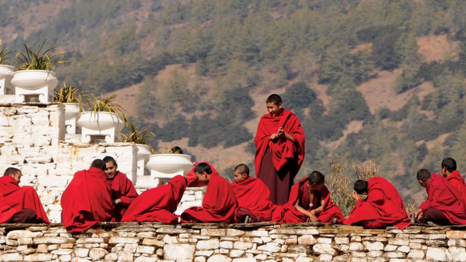 Bhutanese monks socialise along the monastery wall | Liz Light