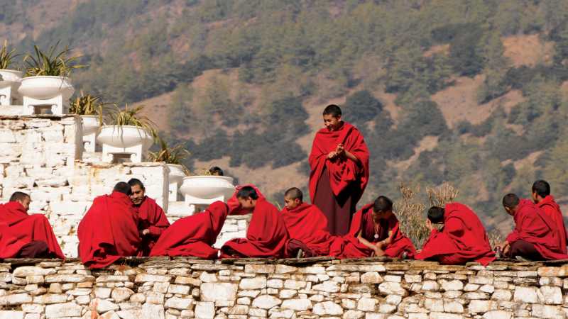 Bhutanese monks socialise along the monastery wall | Liz Light