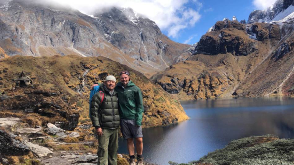 A trekker and guide pose in front of lake Om Tsho on the Bhutan Snowman Trek | Matt Brazier