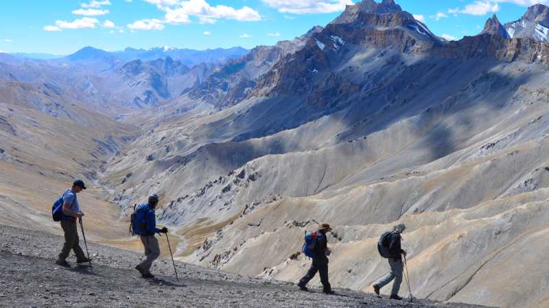 Trekkers making their way across the vast and awe-inspiring landscape of the Zalung La pass, framed by the majestic peaks of Ladakh. | Garry Weare