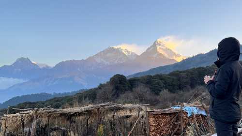 A World Expeditions trekker enjoys a warm cup of tea at daybreak to the breathtaking views of the Annapurna massif from our exclusive eco campsite at Pulbari | Sue Badyari