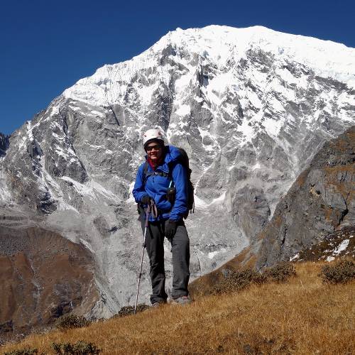 Mountaineer descending to base camp from Yubra Himal High Camp with Langtang Lirung in the background.