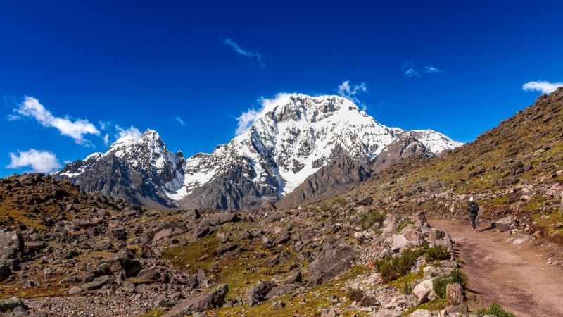 Trekking a rocky trail beneath snow-capped peaks in the Ausangate Mountains, Peru - Ausangate Trek, Peru