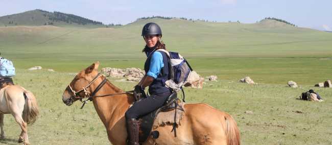 World Expeditions Rider on horseback crossing Mongolia’s green steppe, deep in nomadic country